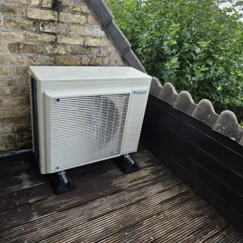 Daikin-buitenunit op een houten terras in Damme